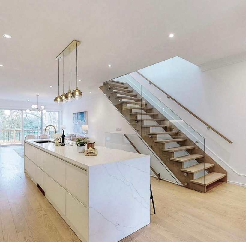 Open oak and glass staircase beside a waterfall-edge kitchen island at Hunt Avenue